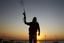 A Libyan rebel shoots in the air at a checkpoint in the Bab El Bahrah district in Tripoli, Tuesday, Aug. 23, 2011.