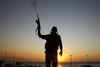 A Libyan rebel shoots in the air at a checkpoint in the Bab El Bahrah district in Tripoli, Tuesday, Aug. 23, 2011.