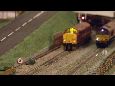 A Class 37 pauses at the signal as a passing freight train runs south.