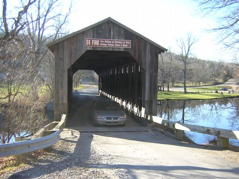 Vehicle crossing to the west. $5 fine sign is visible. The bridge uses the Brown truss system, a through truss consisting of diagonal compression beams and (optionally) almost vertical tension members (slanting in at the top toward the center of the span)