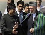 Afghanistan's President Hamid Karzai, right, shakes hands with India's Junior Minister for Foreign Affairs E Ahamed upon his arrival at the airport in New Delhi, India, Tuesday, Oct. 4, 2011.