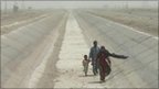 People walk in a dry river bed