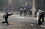 File - A protester throws a stone at Greek police officers, during clashes in central Athens, Wednesday, Oct. 19, 2011. Greek anger over new austerity measures continues.