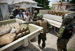 SOMALIA, Mogadishu: In a handout photograph released by the African Union-United Nations Information Support Team, Ugandan officers serving with the African Union Mission in Somalia (AMISOM) and members of the Somali Transitional Federal Government (TFG) Police Force stand next to a haul of 155mm artillery shells that were found in a house deep inside the former insurgent Al Shabaab stronghold of Bakara Market in the Somali capital Mogadishu on 12 July. Local people tipped off TFG police of the