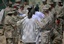 In this photo, reviewed by the U.S. military, guards stand on either side of a line-up of Guantanamo detainees, in white, to perform a search for unauthorized items, at Guantanamo's Camp 4 detention facility, at Guantanamo Bay U.S. Naval Base, Cuba, Tuesday, May 12, 2009.