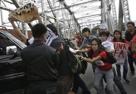 Protesters opposing the visit of U.S. Secretary of States Hillary Rodham Clinton rush forward as a member of the security convoy try to stop them Wednesday, Nov. 16, 2011 in Manila, Philippines.