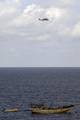 An SH-60 Sea Hawk helicopter assigned to the Scorpions of Helicopter Anti-Submarine Squadron (HS) 49 Light flies near a suspected pirate vessel towing a skiff.