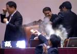 Rep. Kim Seon-dong, bottom, of the opposition Democratic Labor Party, explodes tear gas in front of the speaker's chair to block National Assembly Vice Speaker Chung Eui-hwa, center, from pushing for the procedure to handle a pending bill on ratification of a South Korea-U.S. free trade agreement at the National Assembly in Seoul, South Korea, Tuesday, Nov. 22, 2011. South Korea's parliament ratified a long-stalled free trade deal with the United States on Tuesday after ruling party lawmakers fo