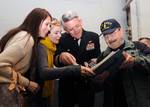 Capt. William C. Hamilton Jr., center, commanding officer of the aircraft carrier USS Enterprise (CVN 65), visits with retired sailors and visitors as they look at a cruise book from 1967.