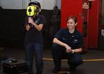 Hull Maintenance Technician Fireman Sarah R. Pixley shows a Navy firefighter's thermal imager, the ISG/Infrasys K-90 Talisman, to a child during the birthday celebration for the aircraft carrier USS Enterprise (CVN 65).