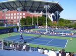 The USTA Billie Jean King National Tennis Center, showing Courts #6 and 5, part of the practice courts (on the left), and Arthur Ashe Stadium in the background, taken on Arthur Ashe Kid's Day in 2010.