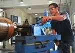 Machinery Repairman Fireman Darryl Dayrit, assigned to the submarine tender USS Frank Cable (AS 40), operates a gap lathe machine.