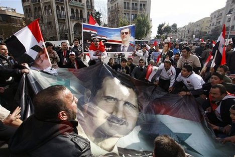 Pro-Syrian regime protesters hold a rally in support of President Bashar Assad, pictured in the large banner, in Damascus, Syria, Friday, Dec. 9, 2011. Syrian forces killed at least six people - including two children - as they fired on anti-government demonstrations across the country on Friday