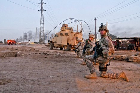 Military policemen assigned to Headquarters Company, 2nd Brigade Special Troops Battalion, 2nd Brigade, 82nd Airborne Division, take a knee during a dismounted patrol along a road outside Camp Taji, Iraq, Dec. 2, 2011.