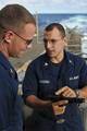 Operations Specialist 2nd Class Anthony Faccioli, right, verifies a clear and safe 9 mm pistol with Ensign Austin Ayres