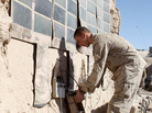 In this photo released by the U.S. Marines and taken in December 2010, Lance Cpl. Dakota Hicks, from Laharpe, Ill., connects a radio battery to a portable solar panel communication system in Sangin District, in Afghanistan.The U.S. military is trying to wean itself off reliance on fossil fuels by employing solar energy and biofuels, among other measures.