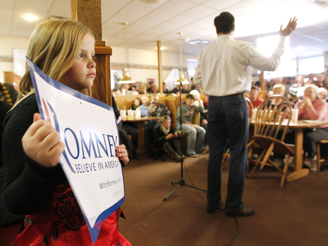 A young supporter backs former Massachusetts Gov. Mitt Romney as he speaks on Wednesday at Homer's Deli and Bakery in Clinton, Iowa.