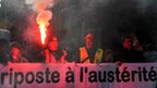 A man holds a flair during a protest against the French government's austerity measures