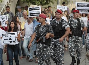 Lebanese policemen, right, secure anti-Syrian regime protesters who they hold up Arabic placards read:"The crime of the regime in hour, arresting, kidnapping and killing, foreground, Yes for freedom Syria, yes for freedom Bahrain, yes for the revolution whenever it was," as they protest during a demonstration to show their support to the Syrian protesters, in Beirut, Lebanon, on Monday Aug. 15, 2011. Syrian troops besieged residential areas of two key cities Monday, firing on residents as they fled for safety and killing at least two people during broad military assaults to root out dissent against President Bashar Assad's autocratic regime, witnesses said. (AP Photo/Hussein Malla)