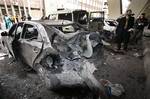 Syrian investigators, right, inspect next to a damaged car at the scene of a bomb in Midan neighborhood of Damascus, Syria, on Friday Jan. 6, 2012.