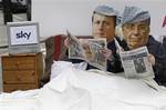 Protesters wearing masks depicting Britain's Prime Minister David Cameron, left, and News Corporation owner Rupert Murdoch lie in a bed after the British government approved plans by News Corp. to buy full control of satellite TV operator British Sky Broadcasting Group PLC in central London, Thursday, March 3, 2011. In a controversial move, the Conservative-led coalition said Thursday it will give News Corp. the green light to buy the remaining 61 percent of BSkyB it does not already own _ on th