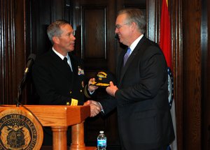 Rear Adm. Michael McLaughlin presents a group ball cap to Missouri Gov. Jay Nixon during a news conference.