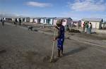 In this picture taken on Jan. 6, 2012, a woman sweeps the road near new homes being built for people displaced by the 2010 earthquake in Zoranje, Haiti. As the hemisphere's poorest country marks the second anniversary of the earthquake that killed some 300,000 people, only about half of the $4.6 billion in promised aid has been spent, half a million people are still living in crowded camps and only four of the 10 largest projects funded by international donors have broken ground.