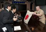 Lt. j.g. Michael Reid unveils a World War II-era Japanese flag to reporters from the Yokosuka Press Club.