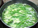 A saucepan containing garlic chive flowers and soft tofu