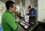 Logistics Specialist 3rd Class Joel Dunbar, from Boulder City, Nev., assists Aviation Ordnanceman Airman Eric Terrell, from Cleveland, with postage in the post office aboard the Nimitz-class aircraft carrier USS John C. Stennis (CVN 74).