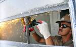 Steelworker 1st Class Honer Villanueva uses an angle grinder to remove steel bars from a door at a GMT engineering civil action project as part of Pacific Partnership.