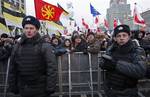 Russian police officers guard protesters during a rally against alleged vote rigging in Russia's parliamentary elections on Sakharov avenue in Moscow, Russia, Saturday, Dec. 24, 2011.