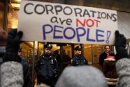 A member of the Occupy Wall Street movement lifts a protest sign in front of NYPD officers guarding the Pfizer building during a "national day of action" demonstration by the movement in New York City on Wednesday.