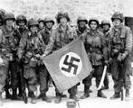 101st Airborne troops posing with a captured Nazi vehicle air identification sign two days after landing at Normandy.