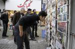 Iranians look at newspapers on a news stand in central Tehran, Iran, on Saturday, Feb. 25, 2012, ahead of March 2 parliamentary elections, which mark the first test of popularity for President Mahmoud Ahmadinejad since his disputed 2009 re-election. The March 2 vote will be especially hard fought between Ahmadinejad's supporters and opponents within the conservative camp, and should _ for a time at least _ shift attention from Iran's dispute with the West over its nuclear program back to the pol