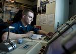 Aviation Machinist's Mate 3rd Class Leo Barth records data from a test run on the engine of a F/A-18C Hornet aboard the aircraft carrier USS Enterprise (CVN 65).