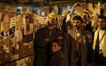 With a poster of Yemen's President-elect Abed Rabbo Mansour Hadi is seen, left, protesters gather as the official results of the country's presidential election are being announce at Taghyeer (Change) Square, where protesters have been camping at for around one year to demand the resignation and trial of Yemen's President Ali Abdullah Saleh in Sanaa, Yemen, Friday, Feb. 24, 2012. Yemen's election commission says 65 percent of registered voters in the country cast their ballot for Vice President