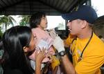 Lt. Robert Hanson, assigned to the submarine tender USS Frank Cable (AS 40), performs a medical examination on a Filipino woman.