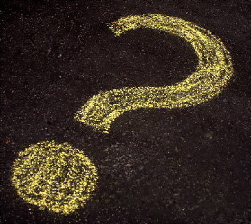 yellow question mark chalked on a tarmac road