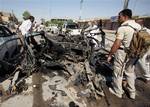 Iraqi security forces inspect the site of a suicide car bomber plowed his vehicle into a checkpoint outside a police building just outside the holy city of Najaf, Iraq, Monday, Aug. 15, 2011.