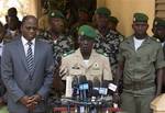 Coup leader Capt. Amadou Haya Sanogo, center, is accompanied by Burkina Faso Foreign Affairs Minister Djibril Bassole, left, as he addresses the press at junta headquarters in Kati, outside Bamako, Mali Sunday, April 1, 2012.