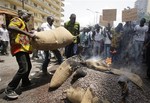 Cocoa growers protest an export ban by burning sacs of cocoa beans in front of the European Union office in Abidjan, Ivory Coast Thursday, Feb. 17, 2011. Other farmers carry signs reading 'No to economic slavery' and 'Shame on the E.U.' as they look on. Ivory Coast's biggest bank shut down its operations Thursday, joining the companies fleeing the country's deepening political crisis, as hundreds of growers in the world's largest cocoa exporter burned their beans in protest.