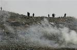 Israeli soldiers walk behind a cloud of teargas during a protest by Palestinian demonstrators, not seen, in the West Bank village of Iraq Burin, near Nablus, Saturday, May 22, 2010.