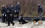 Law enforcement and emergency personnel examine an object on the side of the road, center, near Jones Beach in Wantagh, N.Y., Monday, April 11, 2011. Investigators searching for evidence of a serial killer are hitting the ground around New York's Jones Beach State Park