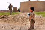 An Afghan boy watches as a U.S. Marine with Weapons Platoon, Alpha Company, 1st Light Armored Reconnaissance Battalion, patrols through a village March 22, 2012. (U.S. Marine Corps photo by Cpl. Alfred V. Lopez/Released)