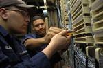 Petty Officer 2nd Class Nick Hernandez shows Fireman Shawn Blackwelder how to 