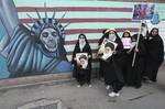 File - Female Iranian school girls stand in front of a satirized drawing of the Statue of Liberty, painted on the wall of the former US Embassy in Tehran, Iran, as they hold posters of supreme leader Ayatollah Ali Khamenei, and anti-US and anti-Israel placards, in an annual state-backed rally, on Friday, Nov. 4, 2011, marking anniversary of the seizure of the US Embassy by militant students on Nov. 4, 1979, when militant Iranian students who believed the embassy was a center of plots against the