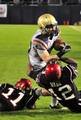 U.S. Naval Academy running back Bo Snelson (#23)is stopped by San Diego State University defensive backs Brandon Davis (#11), left, and Josh Wade (#12) during the 2010 Poinsettia Bowl.