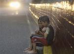 Filipino boys sit together to keep themselves warm as they wait for vehicles to beg for alms in a heavy downpour in Manila, Philippines, Thursday, June 23, 2011. Tropical Storm Meari will be set to make its presence known as it strengthens into a Category 1 typhoon sometime between Friday afternoon and Saturday morning. It will continue on its northwestward to the northeast of the Philippines. (AP Photo/Aaron Favila)