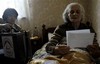 A woman, no name given, looks at her ballot while being visited by an official, left, of mobile election committee, which visits those people that are not able to walk to polling stations, during a parliamentary election in Georgia's separatist South Ossetia province, Tskhinvali, Sunday May 31, 2009.